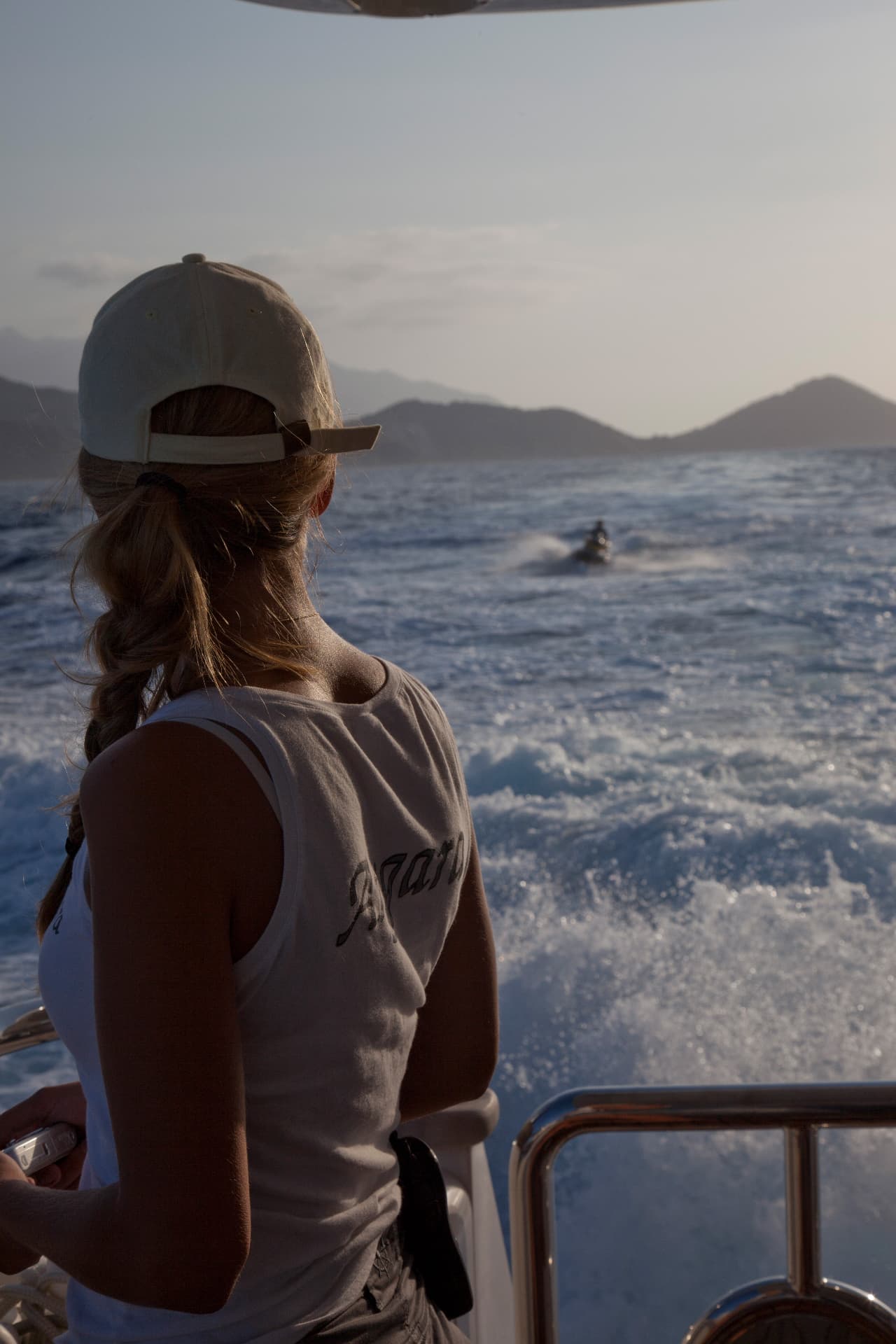 Malin aboard a yacht, looking out over the wake toward a jetski