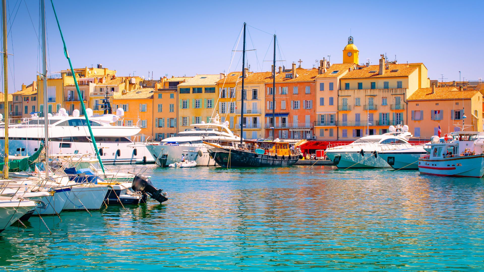 Colorful Saint-Tropez harborfront with yachts and boats moored in bright turquoise water